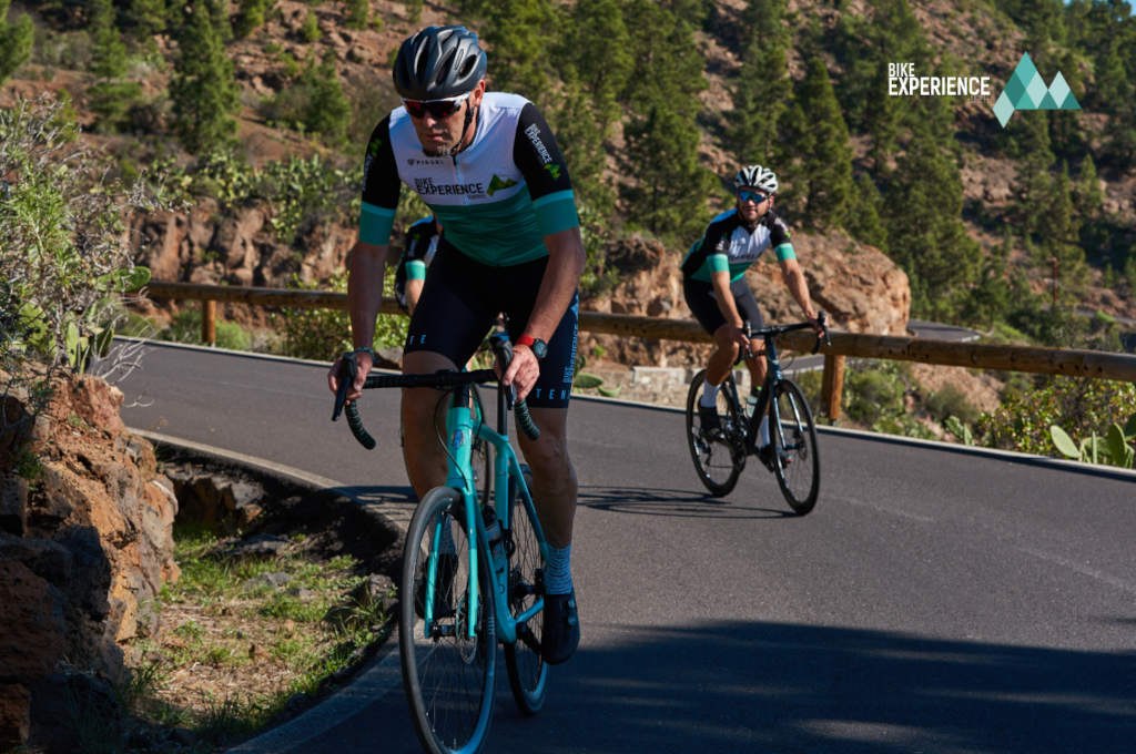 Des cyclistes sur une route montagneuse à Tenerife, paysages forestiers en arrière-plan.