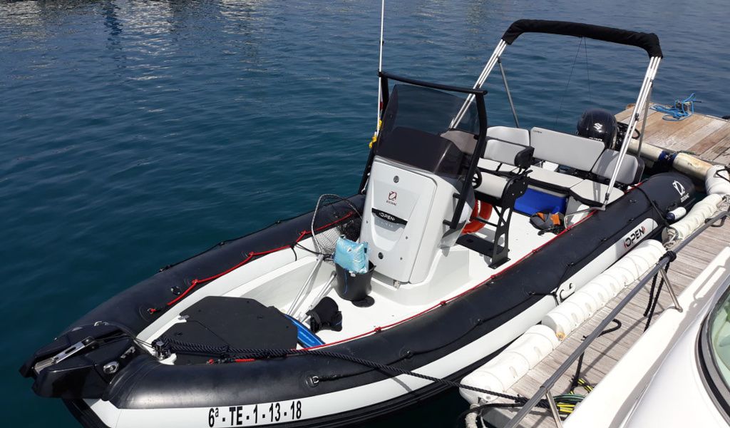 Bateau pneumatique amarré dans le port de Tenerife, avec sièges et moteur visibles.