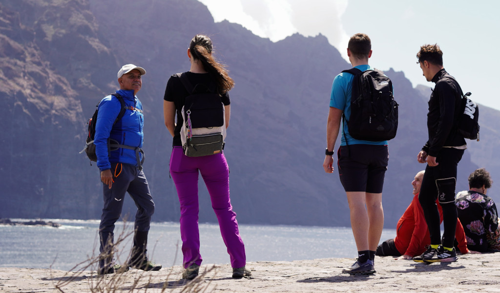 Groupe de personnes avec des sacs à dos devant des falaises à Tenerife.