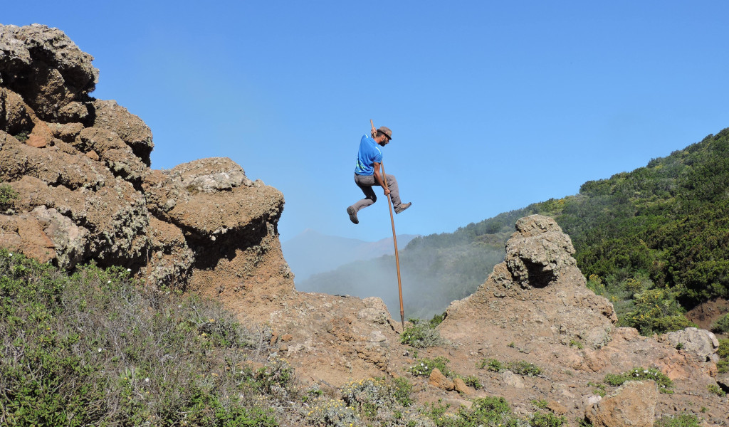 Personne utilisant une massue pour sauter entre des rochers dans un paysage de Tenerife.