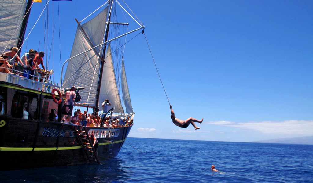 Une personne saute d’un bateau touristique vers la mer sur la côte de Tenerife.