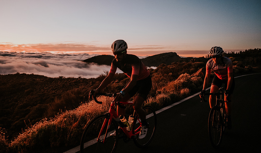 Cyclistes sur route avec un paysage montagneux au coucher du soleil à Tenerife.