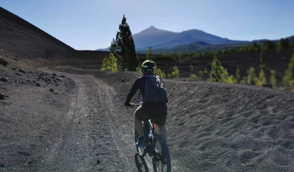 Cycliste sur un sentier volcanique avec le mont Teide en arrière-plan à Tenerife.