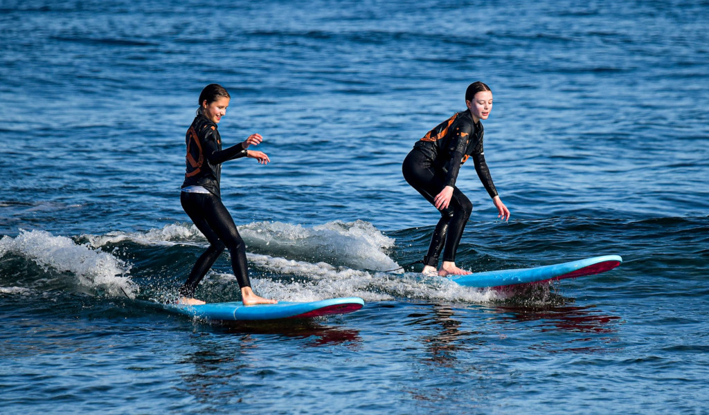 Deux personnes en combinaisons surfent sur de petites vagues dans la mer de Tenerife.