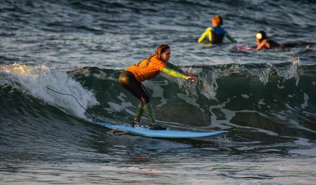Surfeur sur la plage à Tenerife chevauchant une vague au coucher du soleil.
