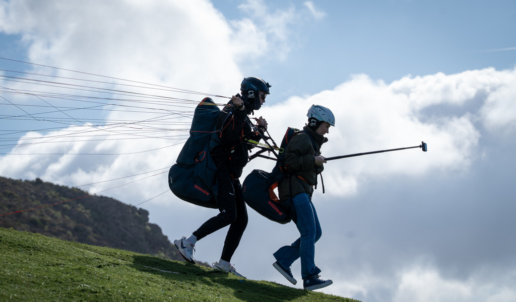 Deux personnes décollant en parapente à Tenerife sous un ciel nuageux.