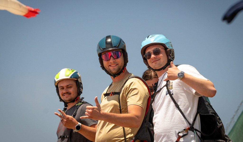 Trois personnes portant un casque sourient en faisant un pouce levé par une journée ensoleillée à Tenerife.