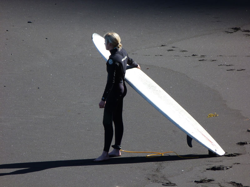 Surfeur sur le sable avec une planche à Playa de Tenerife.