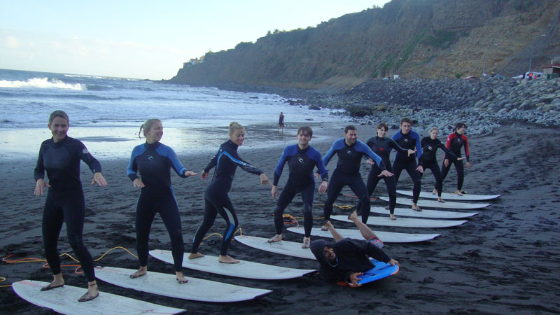 Un groupe de personnes apprend à surfer sur la plage de Tenerife, alignés sur des planches.