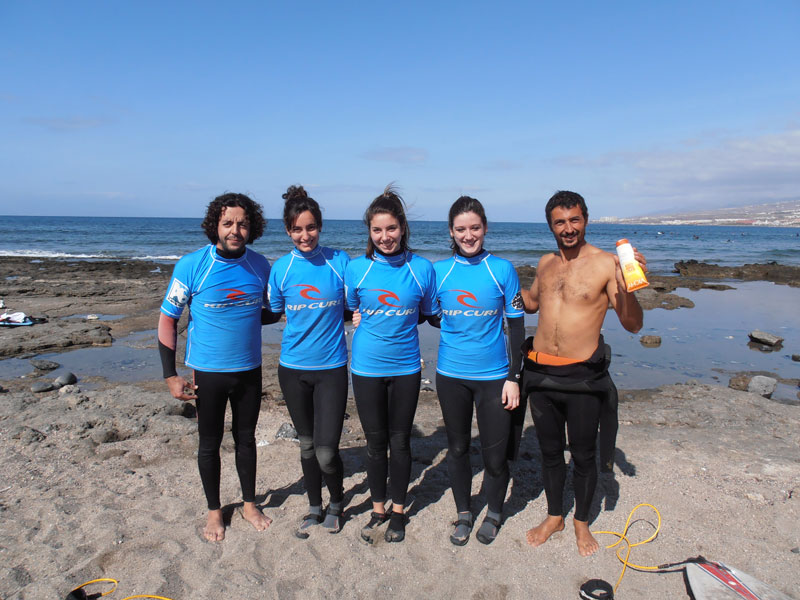 Groupe de surfeurs sur la plage de Tenerife en combinaisons bleues.
