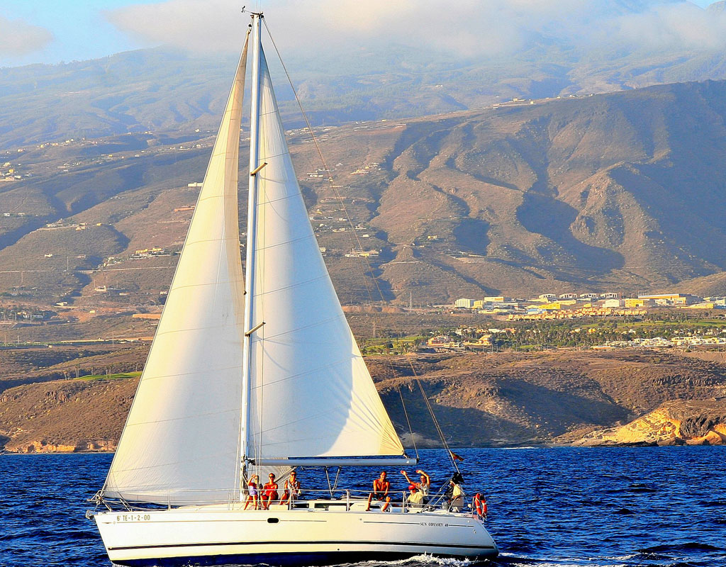 Voilier naviguant près de la côte de Tenerife avec des montagnes en arrière-plan.