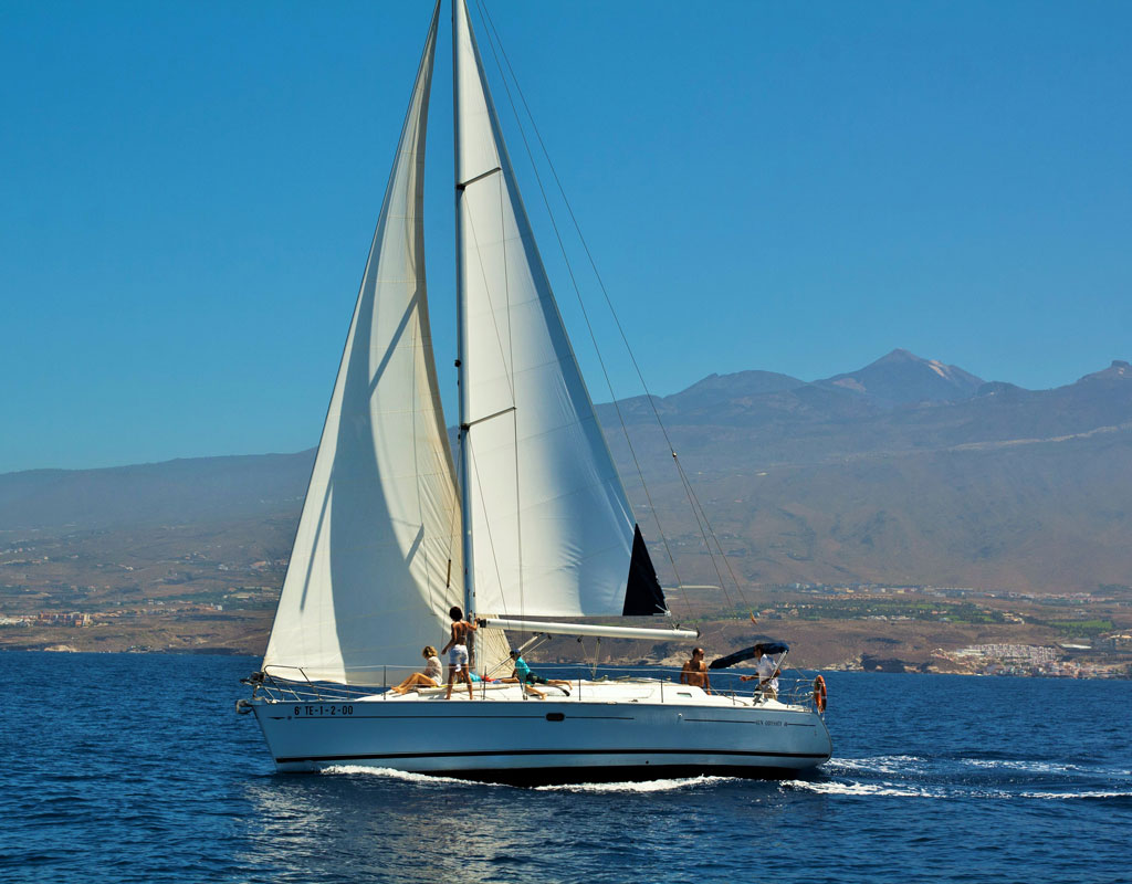 Voilier naviguant au large de Tenerife avec des montagnes en arrière-plan.
