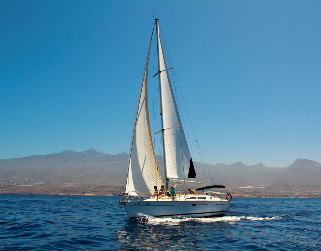 Voilier naviguant au large de Tenerife avec des montagnes en arrière-plan.