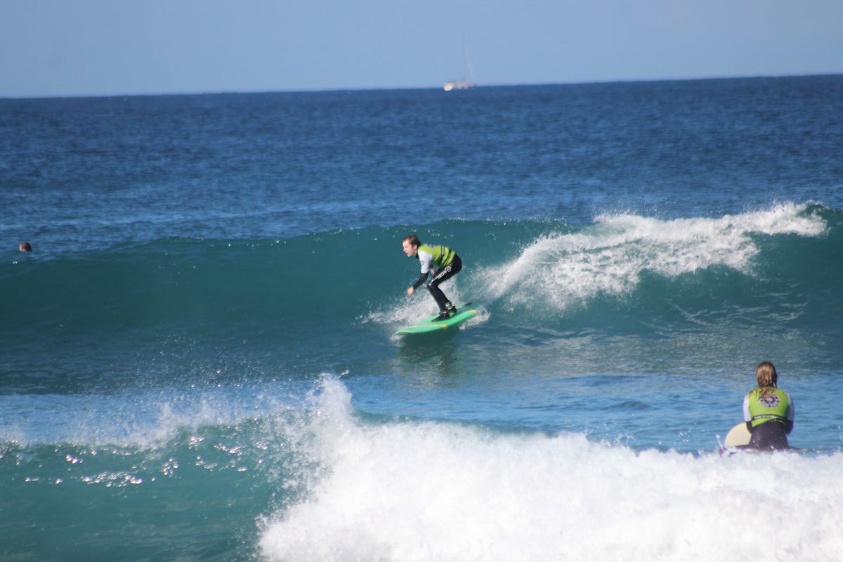 Surfeur chevauchant une vague à Tenerife, avec une autre personne observant depuis l’eau.