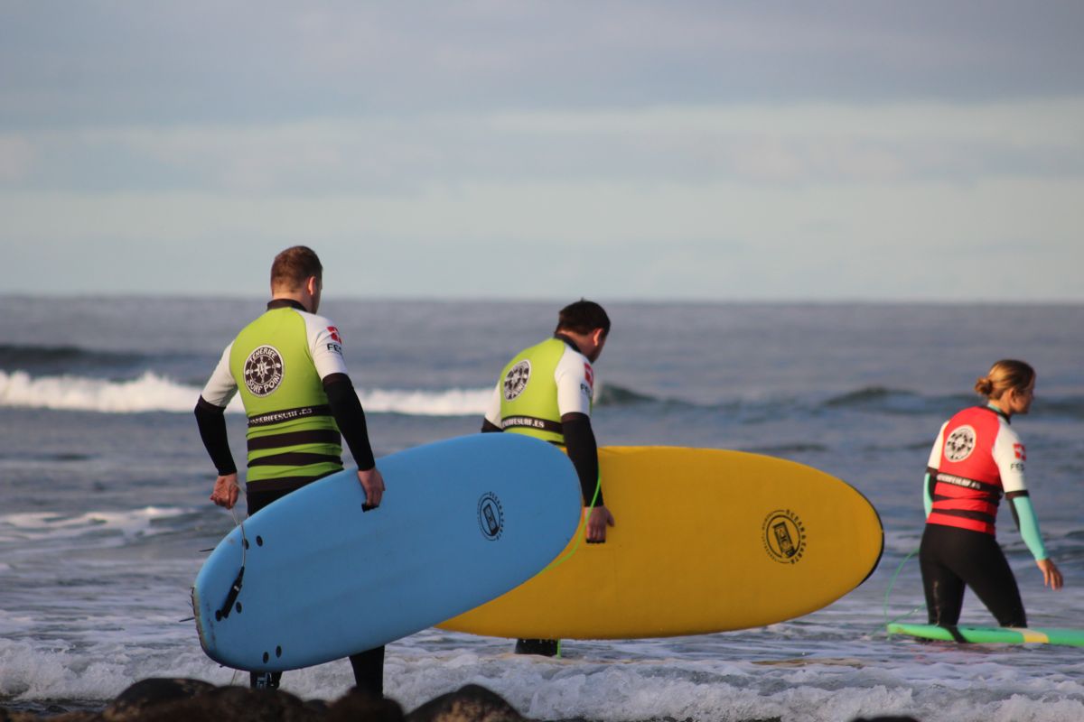 Des surfeurs entrant dans la mer avec des planches colorées à Tenerife.