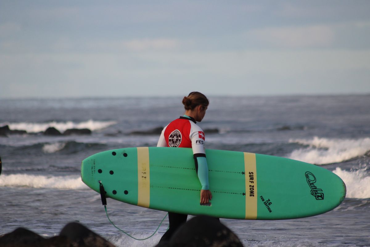 Personne avec une planche de surf verte sur la plage de Tenerife