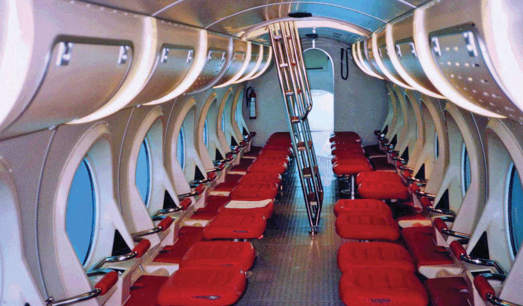 Intérieur d’un sous-marin touristique à Tenerife avec des sièges rouges et de grandes fenêtres.