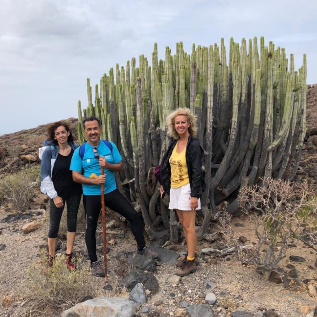 Trois personnes à côté d’un grand cactus dans un environnement rocheux à Tenerife.
