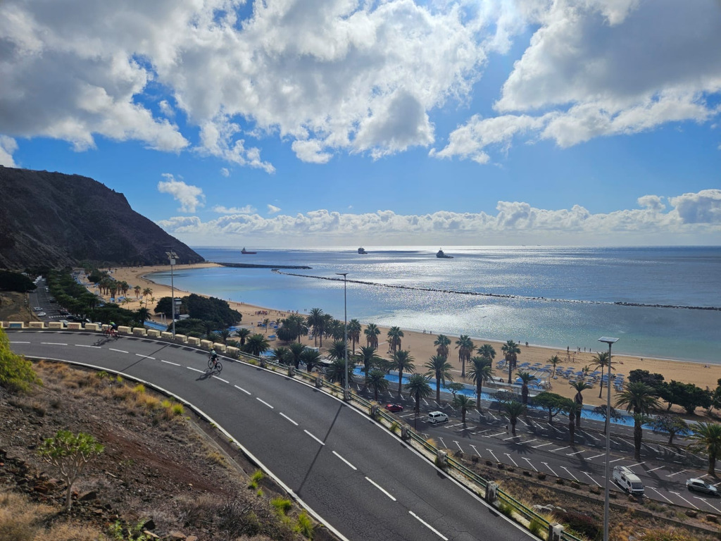 La plage de Las Teresitas à Tenerife avec des cyclistes sur la route et une vue sur la mer.
