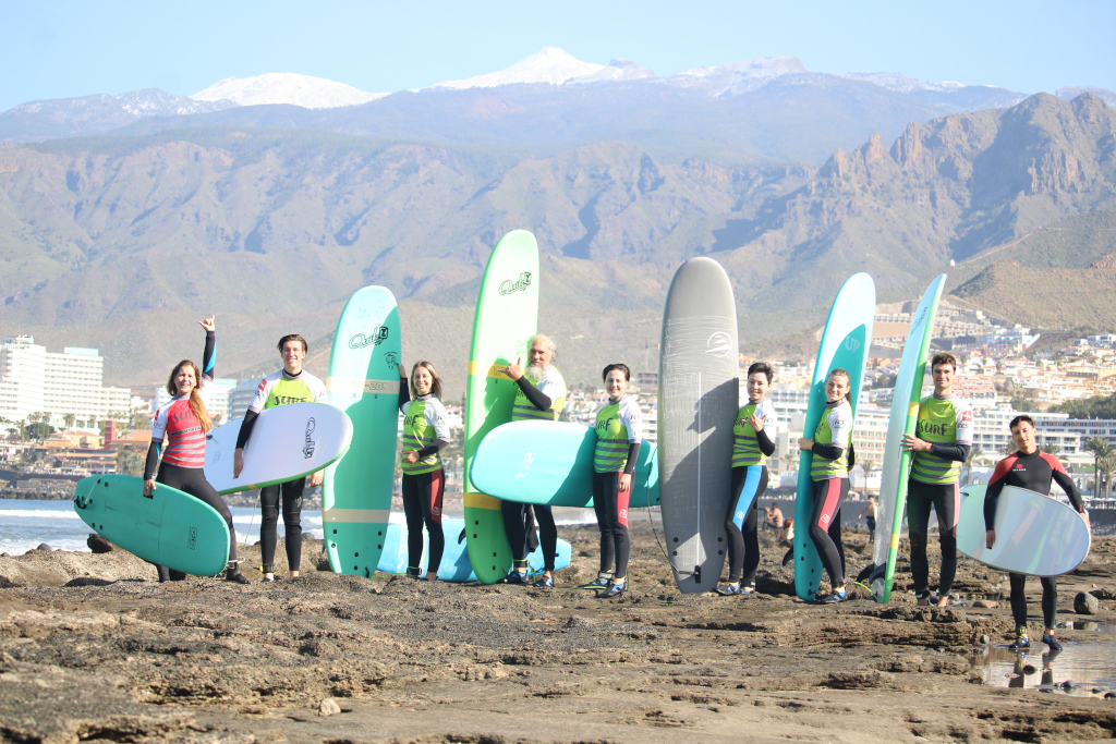 Groupe de surfeurs avec des planches sur la plage de Tenerife, montagnes en arrière-plan.
