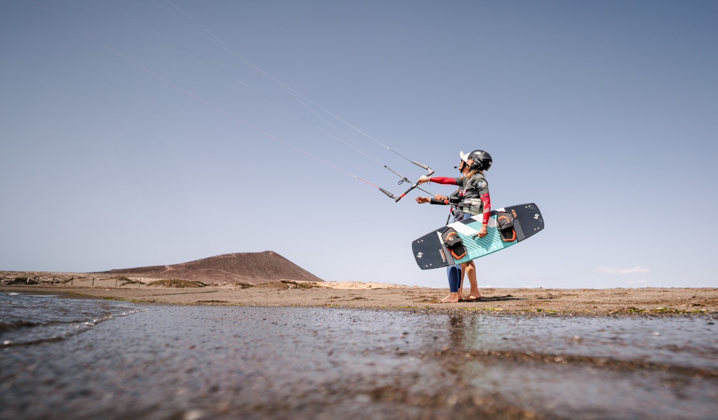 Personne pratiquant le kitesurf à Playa El Médano, Tenerife, avec une colline en arrière-plan.