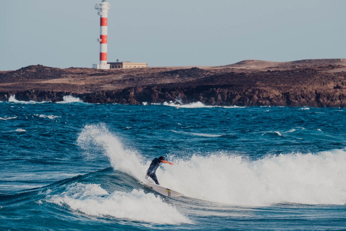 Surfeur chevauchant une vague devant le phare de Punta de Hidalgo, Tenerife.