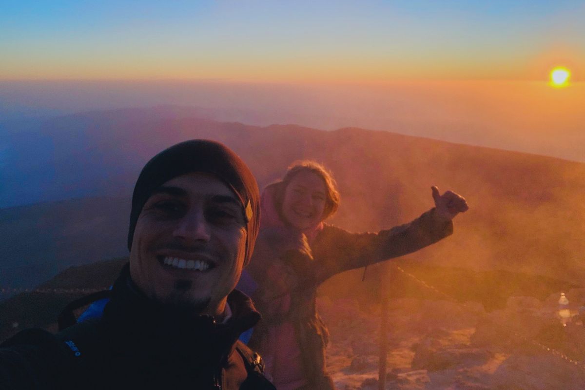 Des gens souriant à l’aube sur le mont Teide, à Tenerife, avec le soleil en arrière-plan.