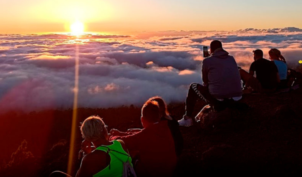 Des gens profitant du coucher de soleil au-dessus des nuages sur le mont Teide, à Tenerife.