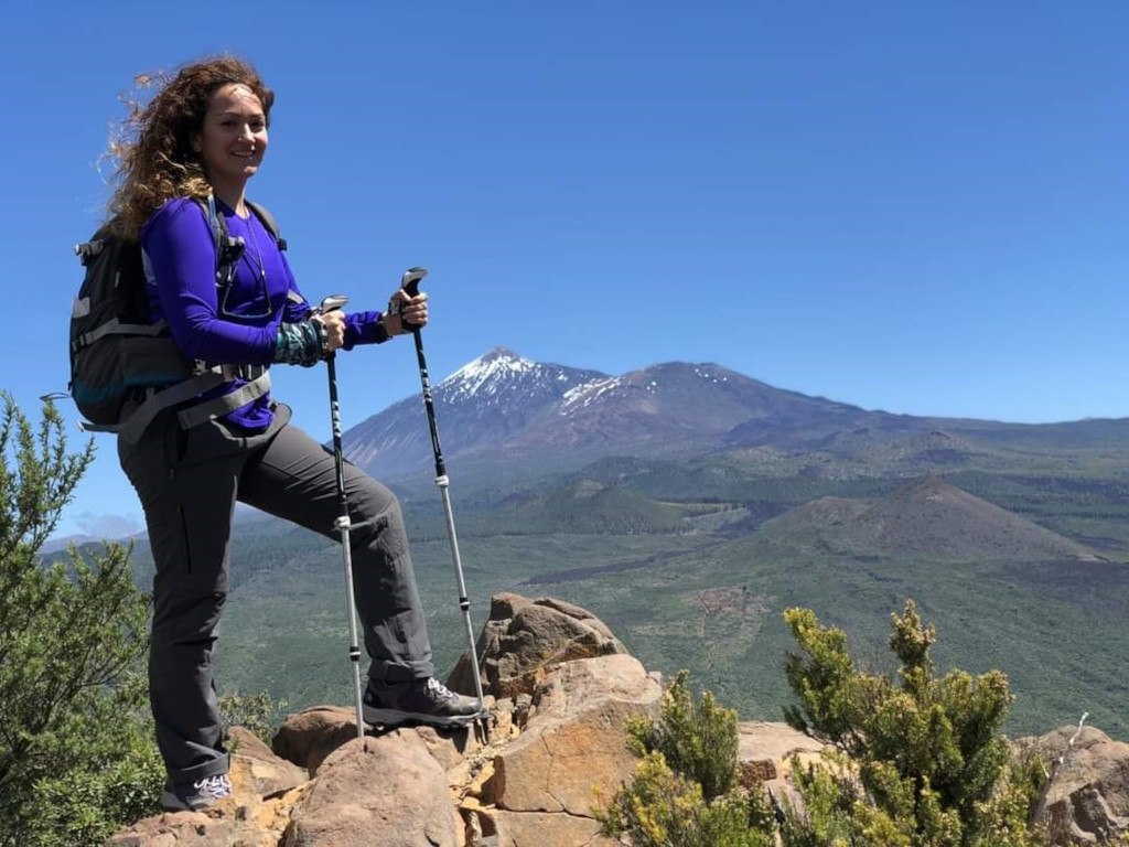 Randonneur avec des bâtons sur un sentier rocheux, avec le mont Teide en arrière-plan, à Tenerife.