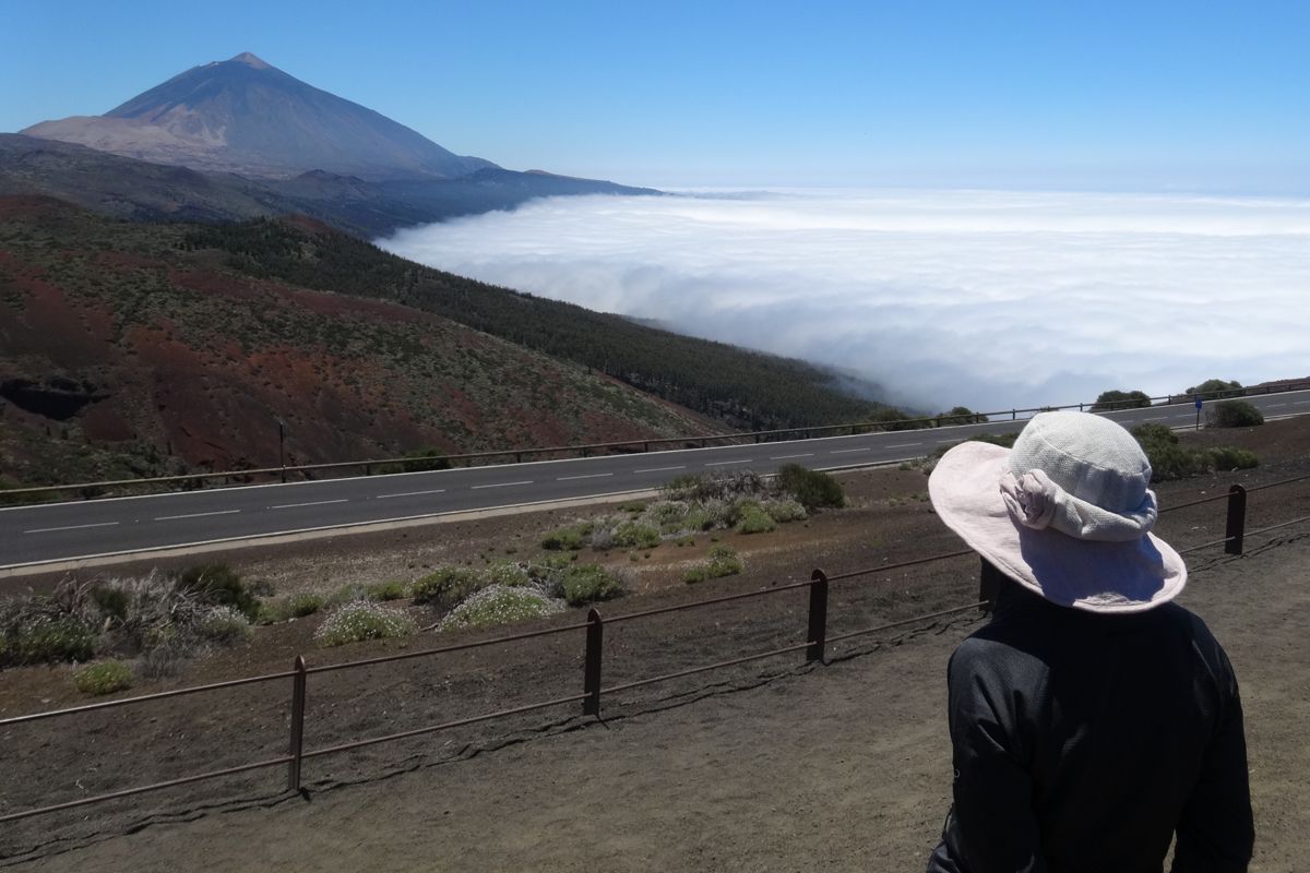 Une personne avec un chapeau regardant la Teide et la mer de nuages à Tenerife.