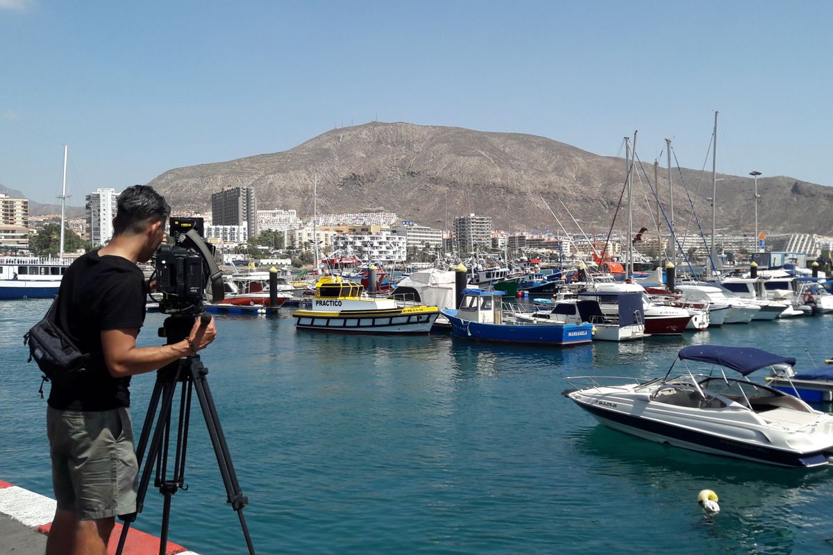 Caméraman filmant des bateaux dans le port de Los Cristianos, Tenerife.