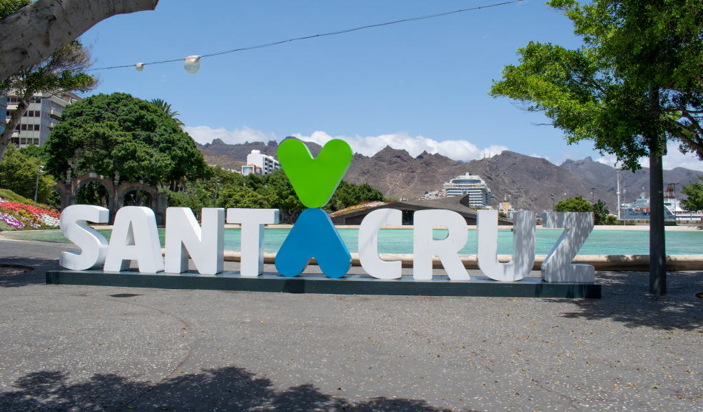Panneau Santa Cruz sur la place avec des arbres et des montagnes en arrière-plan.