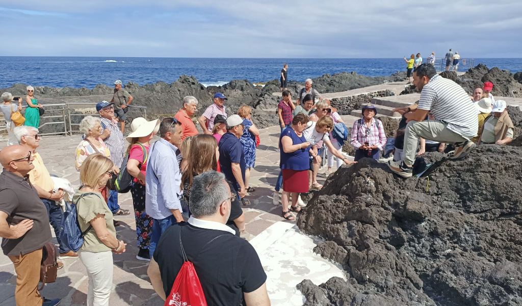 Un groupe de personnes écoute un guide sur les roches volcaniques à Puerto de la Cruz, Tenerife.