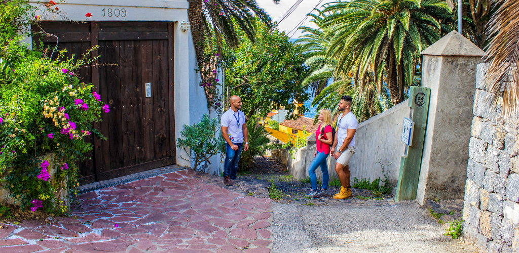 Trois personnes discutant dans une rue entourée de palmiers à Tenerife.