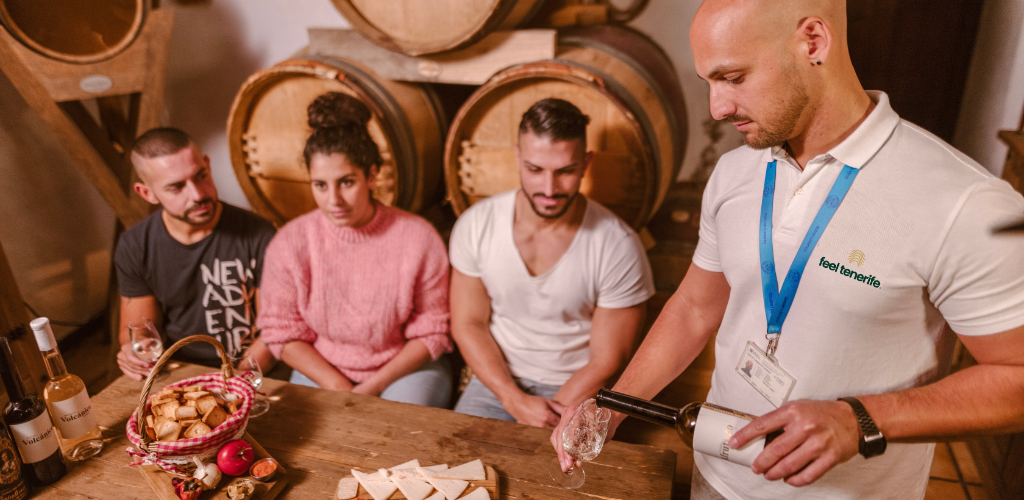 Guide sert du vin à trois personnes dans un domaine viticole à Tenerife.