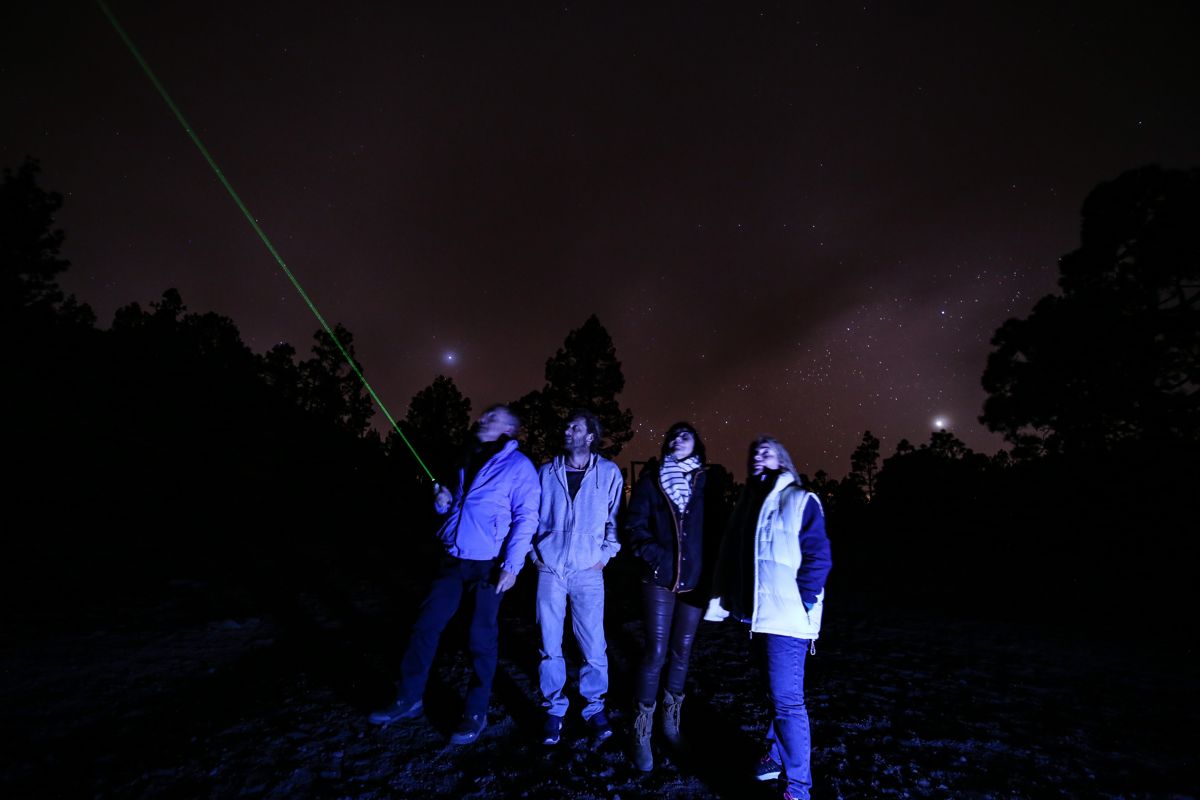 Les gens observent le ciel étoilé à Tenerife, un point laser vert.