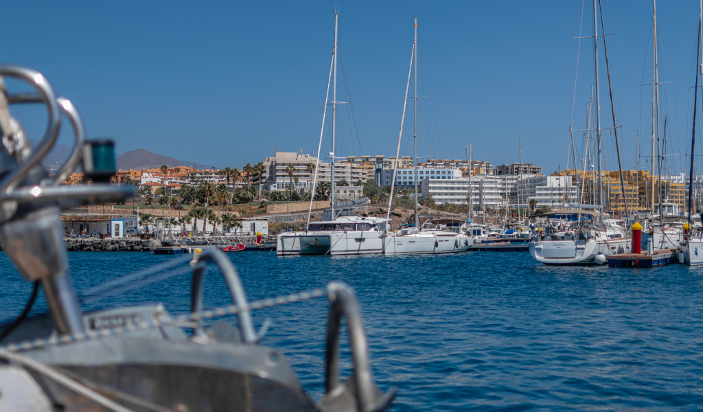 Marina à Costa Adeje, Tenerife, avec des yachts et des bâtiments en arrière-plan.