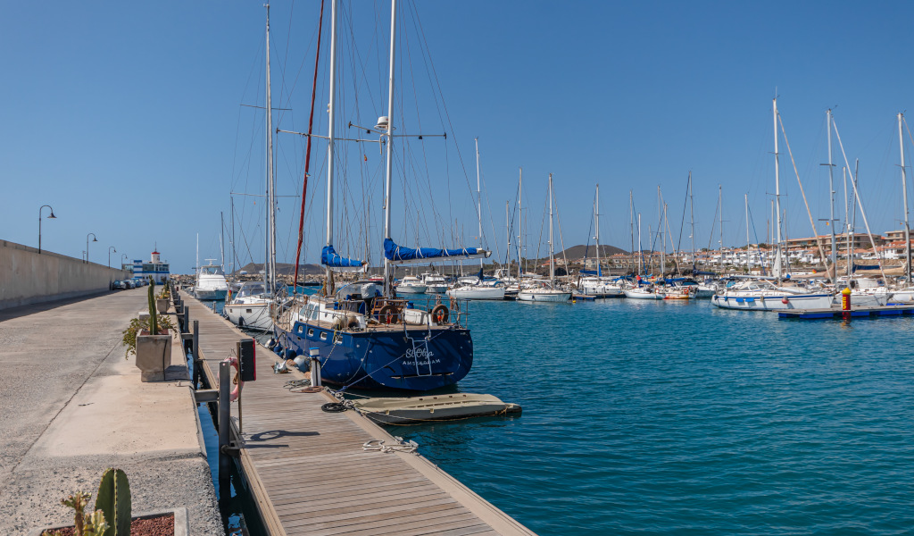 Des bateaux amarrés dans le port de Las Galletas, à Tenerife, avec un phare en arrière-plan.