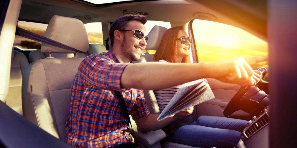 Couple souriant dans une voiture avec une carte à Tenerife au coucher du soleil.
