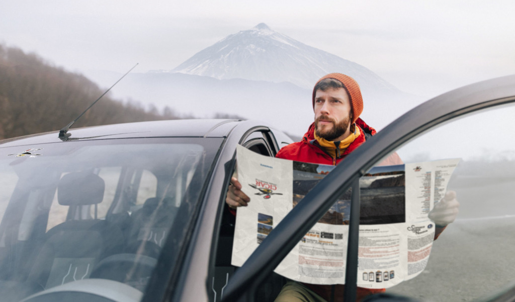 Man consulte une carte à côté d’une voiture avec le mont Teide en arrière-plan, à Tenerife.