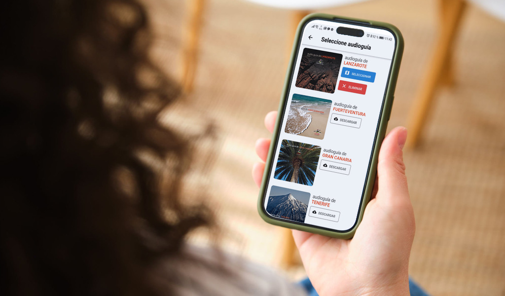 Personne tenant un téléphone portable avec des audioguides de Lanzarote, Fuerteventura, Gran Canaria et Tenerife.