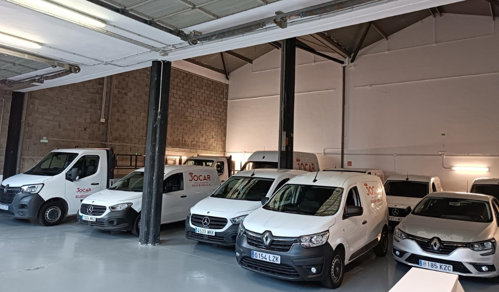 Des véhicules de livraison dans un garage à Tenerife avec le logo Jocar.