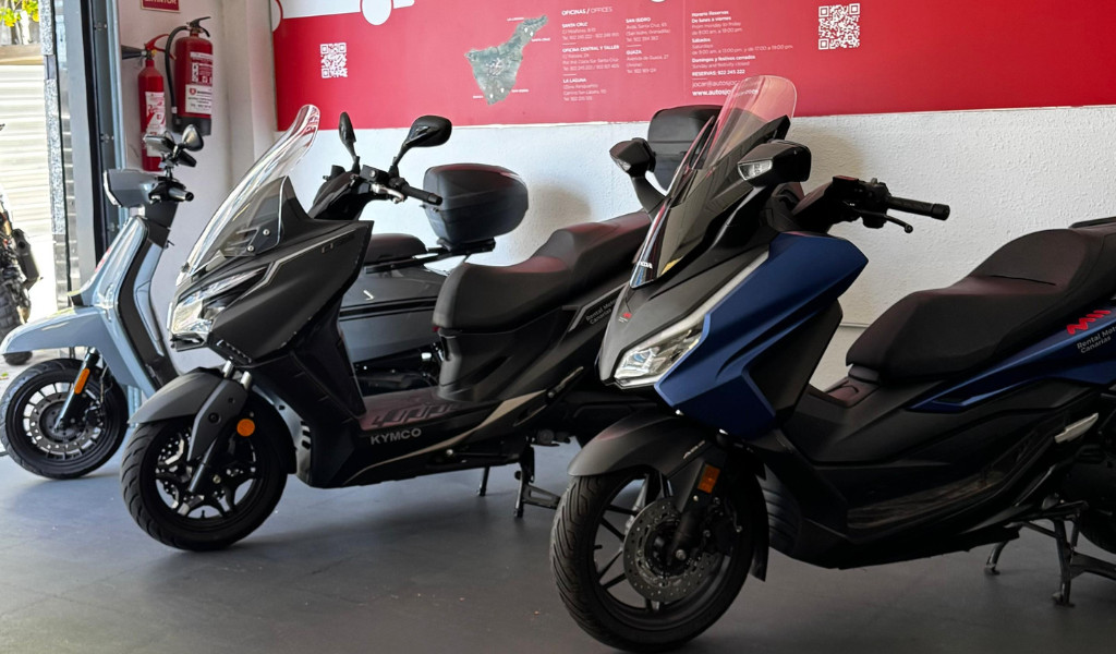 Motos Kymco exposées, en arrière-plan une carte de Tenerife et des extincteurs.