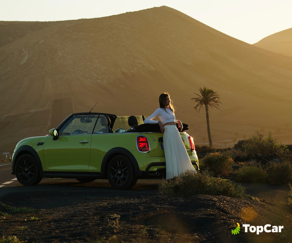Voiture décapotable verte avec une personne devant un paysage montagneux à Tenerife.