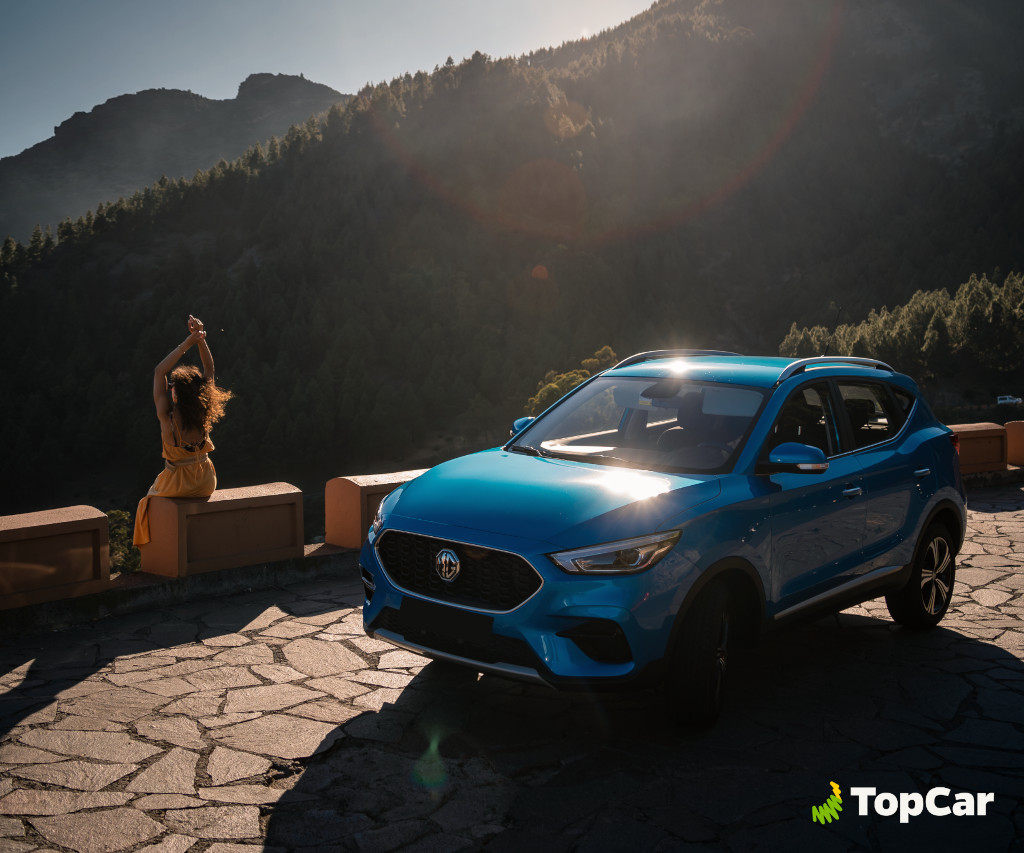Voiture bleue devant les montagnes à Tenerife, femme assise sur un mur sous le soleil.