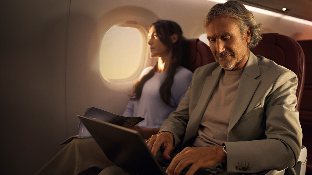 Personne utilisant un ordinateur portable dans un avion, accompagnée d’un passager qui lisait.