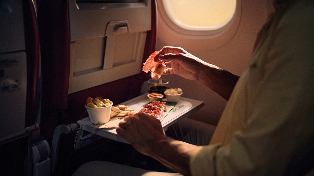 Personne mangeant du jambon serrano dans un avion au-dessus du magazine Turner.