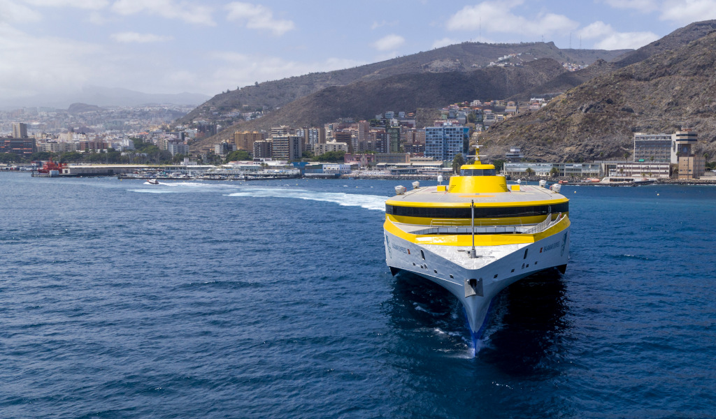 Ferry jaune dans le port de Santa Cruz de Tenerife avec la ville en arrière-plan.