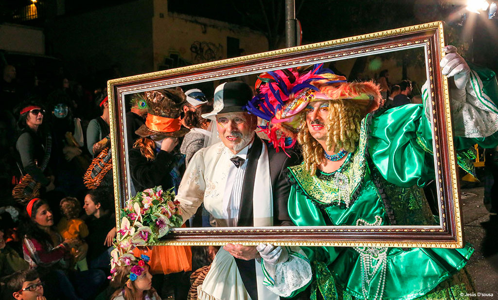 Des personnes en costumes colorés posent derrière un cadre lors du carnaval de Tenerife.