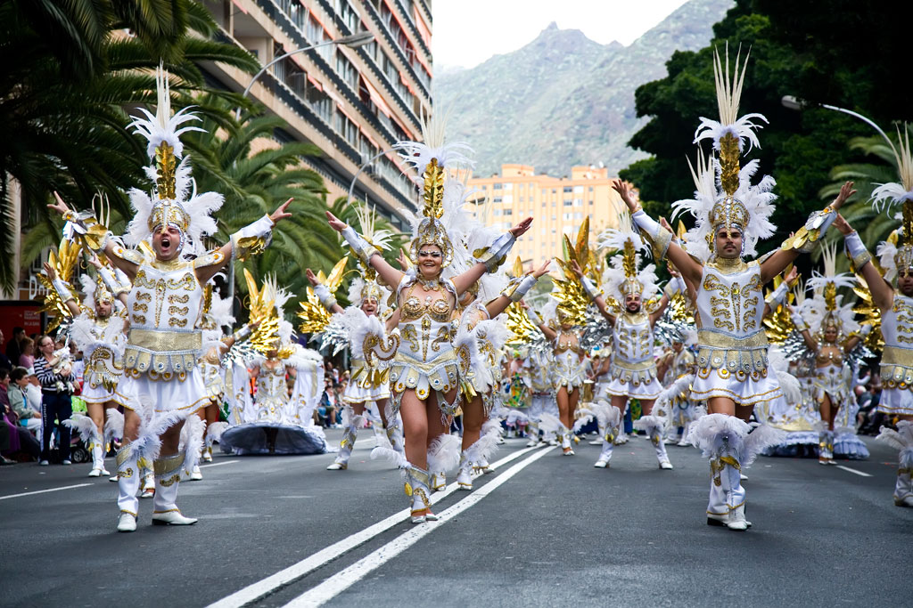 Groupe de personnes en costumes de carnaval dorés et blancs défilant à Santa Cruz de Tenerife.